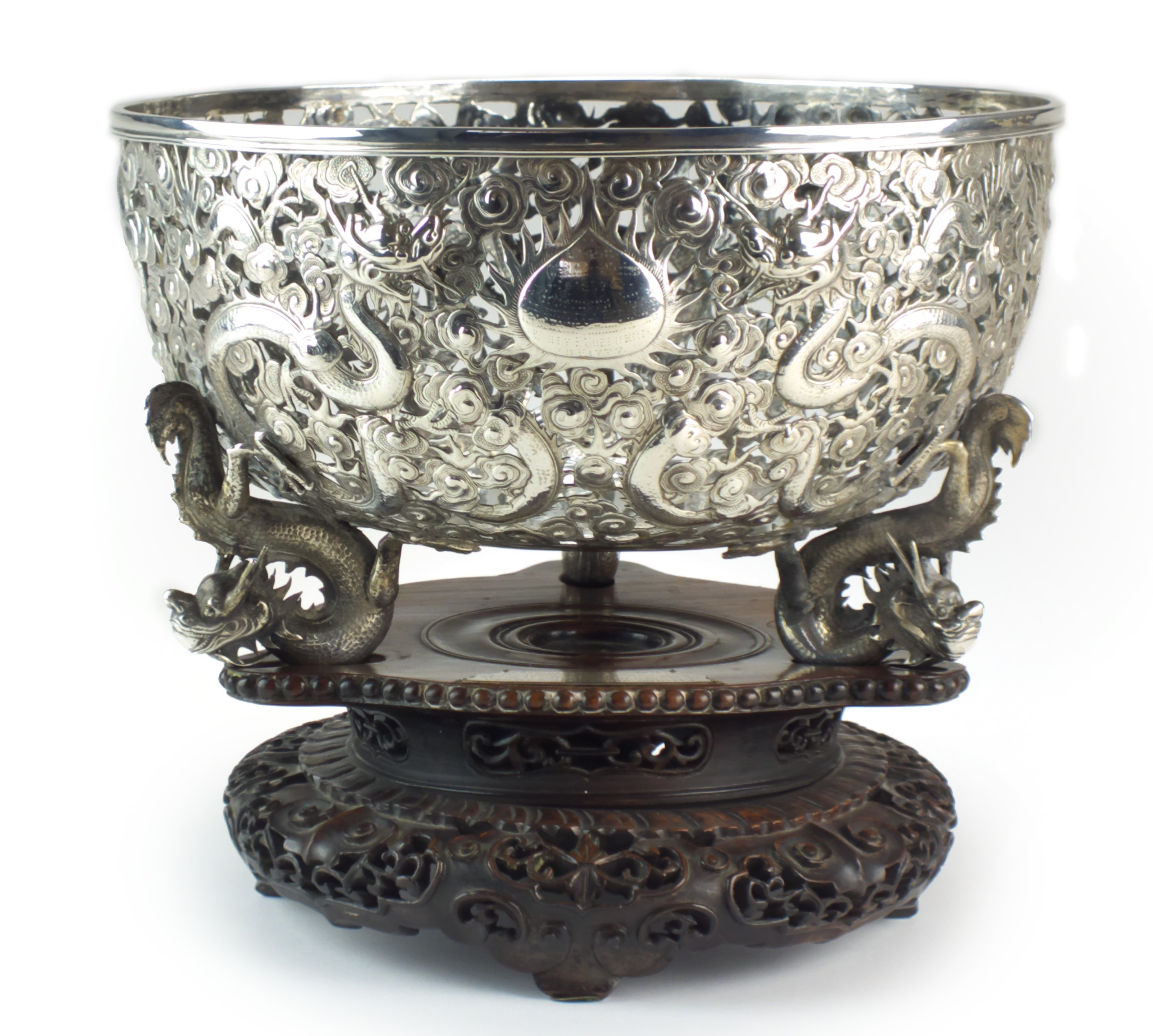 The Governor's Cup: A superb Chinese silver bowl by Wang Hing & Co, dated 1897, of rounded form and raised on three wrythen dragon feet, the openwork sides tooled and chased with multiple dragons in flight amid roiling clouds, a central flaming pearl cartouche inscribed 'Lagos (West Africa) 