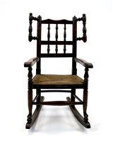 Lot 399 - A child's stained beech and ash rush seat rocking chair