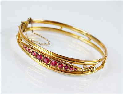 Lot 300 - An Edwardian 9ct gold red paste and diamond set hinged bangle.