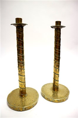 Lot 665 - A tall pair of arts and crafts brass banded candlesticks