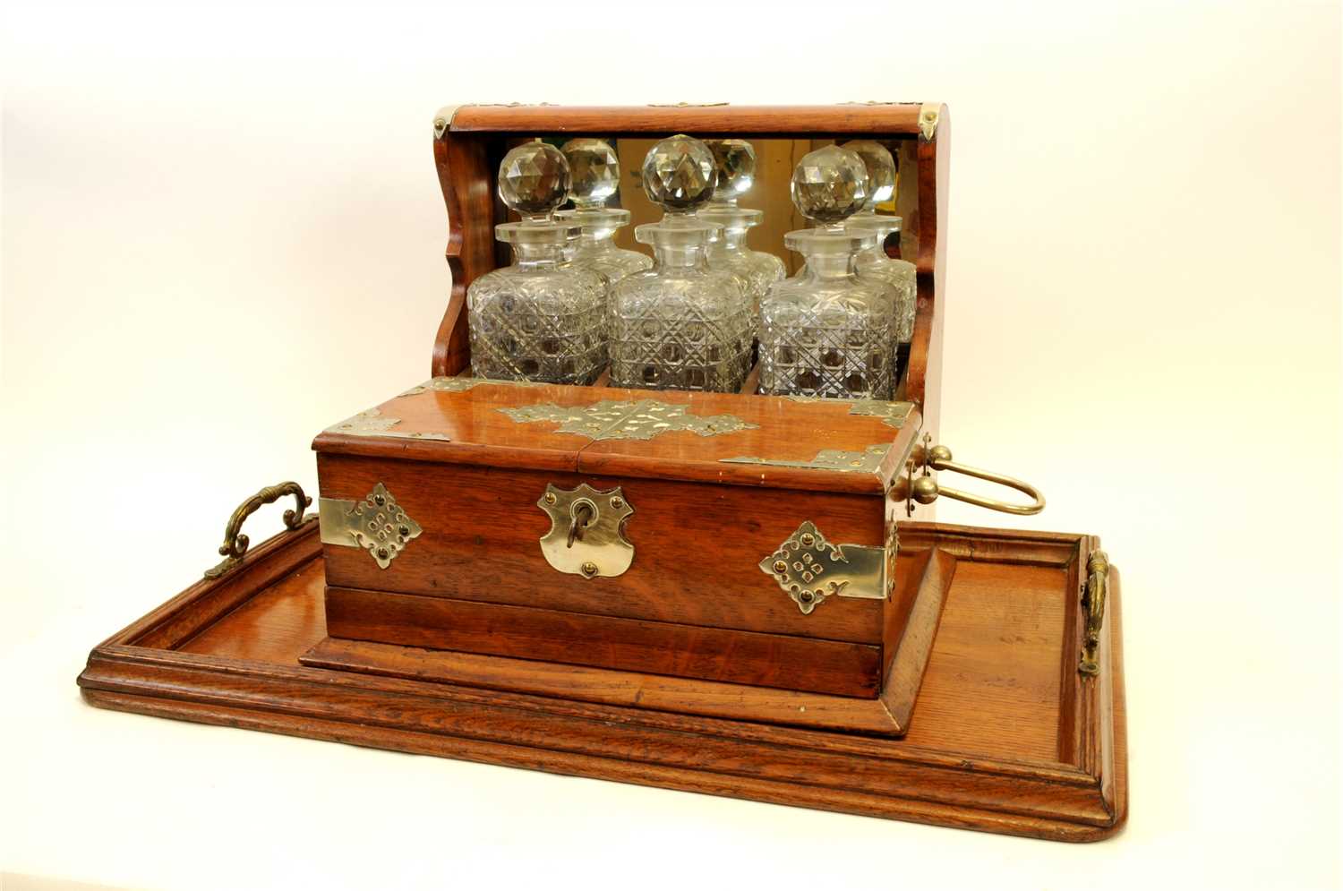 Lot 716 - A Victorian oak three decanter tantalus with silver-plated mounts and an oak drinks tray