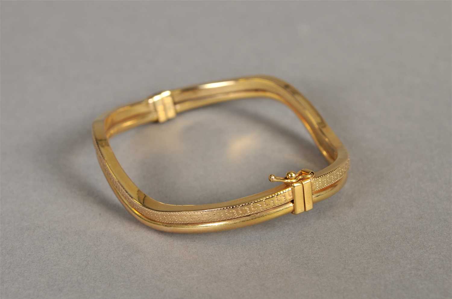 Lot 87 - A 9ct gold stylised wave hinged bangle