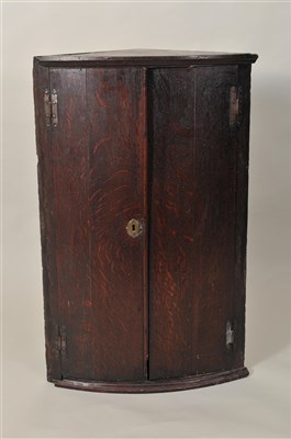 Lot 351 - A small George III rustic country oak barrel-fronted corner cupboard