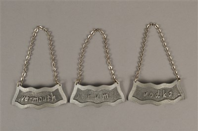 Lot 261 - A trio of pressed pewter decanter labels