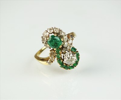 Lot 105 - A diamond and emerald cross over ring