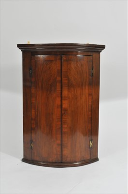 Lot 345 - A 19th century cross-banded walnut veneered barell-fronted corner cupboard