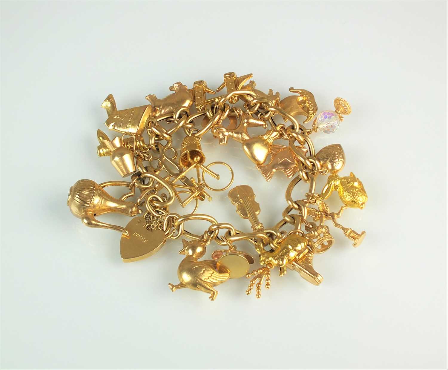 Lot 143 - A 9ct gold hollow curb link bracelet with attached 9ct gold and yellow metal charms