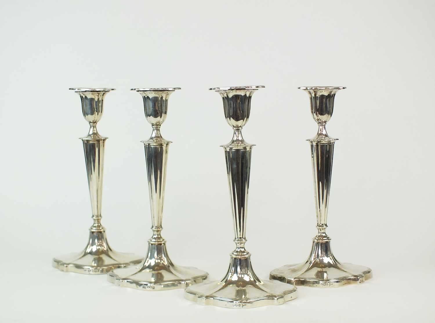 Lot 89 - A set of four silver mounted candlesticks