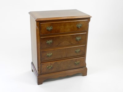 Lot 515 - A small reproduction walnut chest of four long...