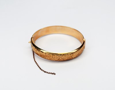 Lot 92 - A 9ct gold bright cut engraved hinged bangle