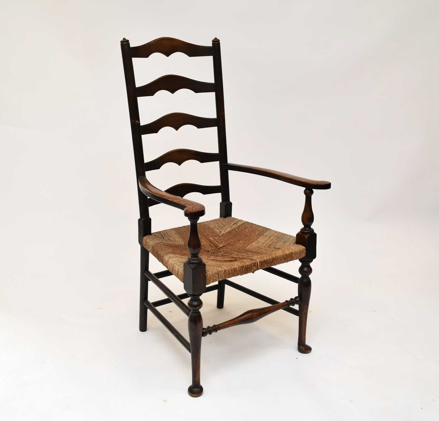 Lot 530 - An oak ladder back rush seated open armchair