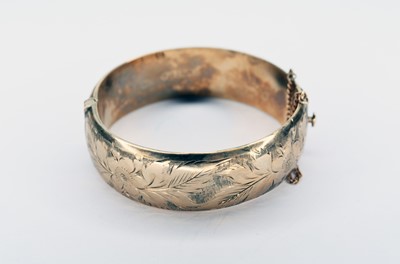 Lot 74 - A 9ct gold bright cut engraved hinged bangle