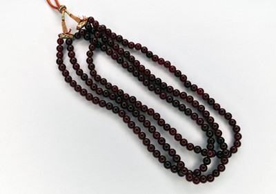 Lot 90 - A three strand polished bead treated ruby necklace