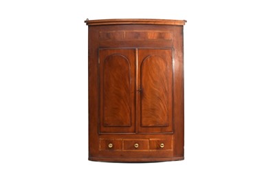 Lot 377 - A George III mahogany cross-banded bowfront panelled hanging corner cupboard