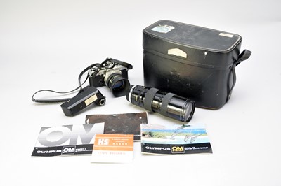 Lot 516 - An Olympus OM-1 35mm SLR camera with case, lenses and papers