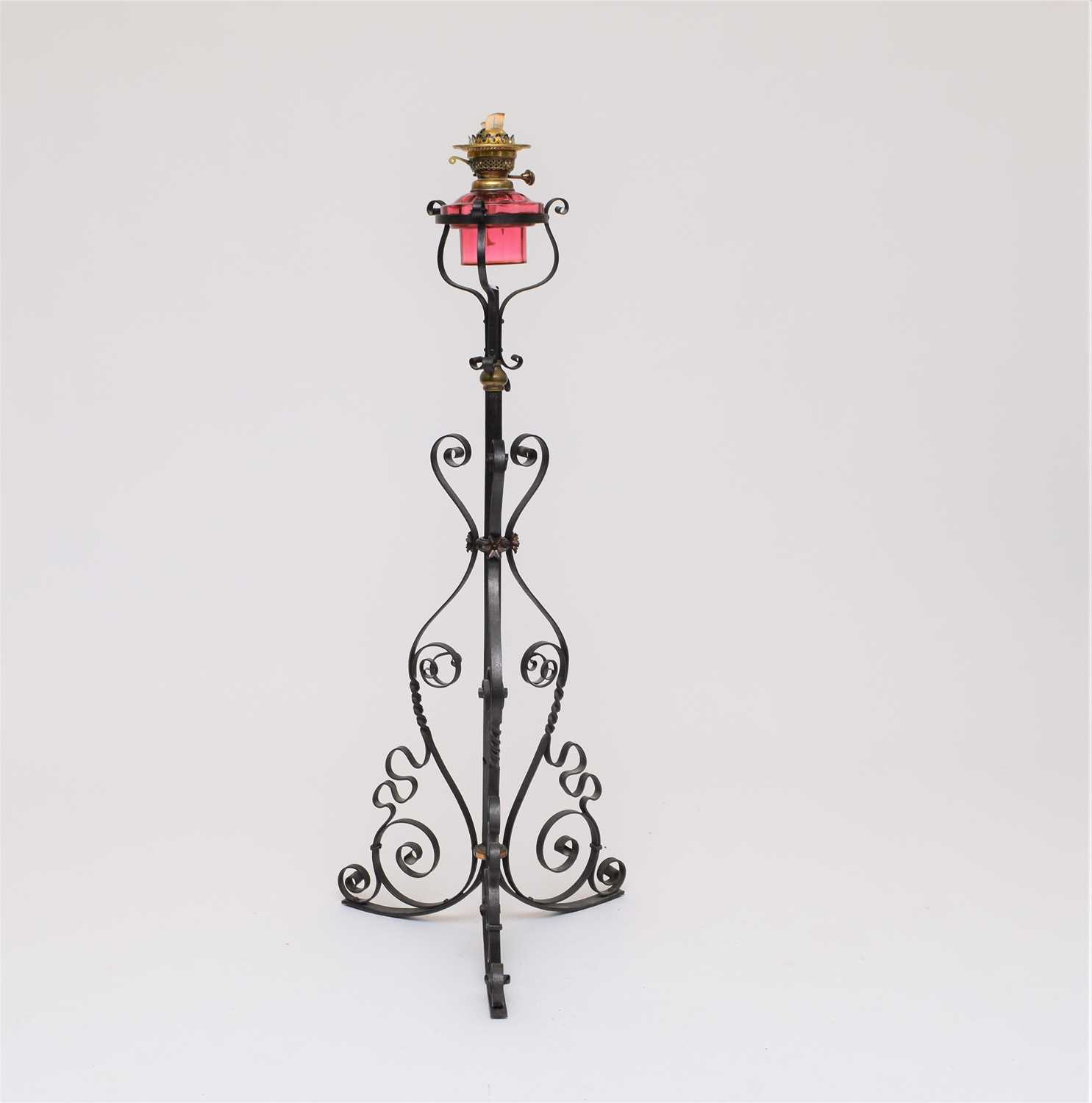 Lot 558 - A wrought iron and cranberry glass oil lamp standard