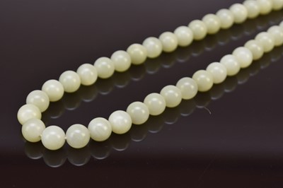 Lot 151 - A pale green jade bead necklace, 20th century