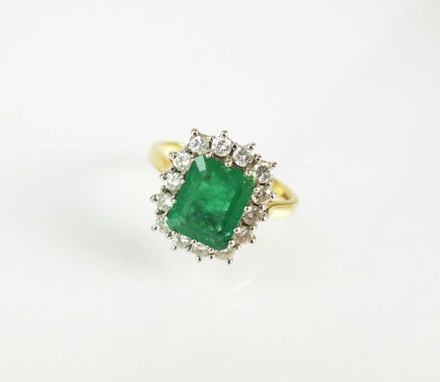Lot 86 - An 18ct gold emerald and diamond cluster ring