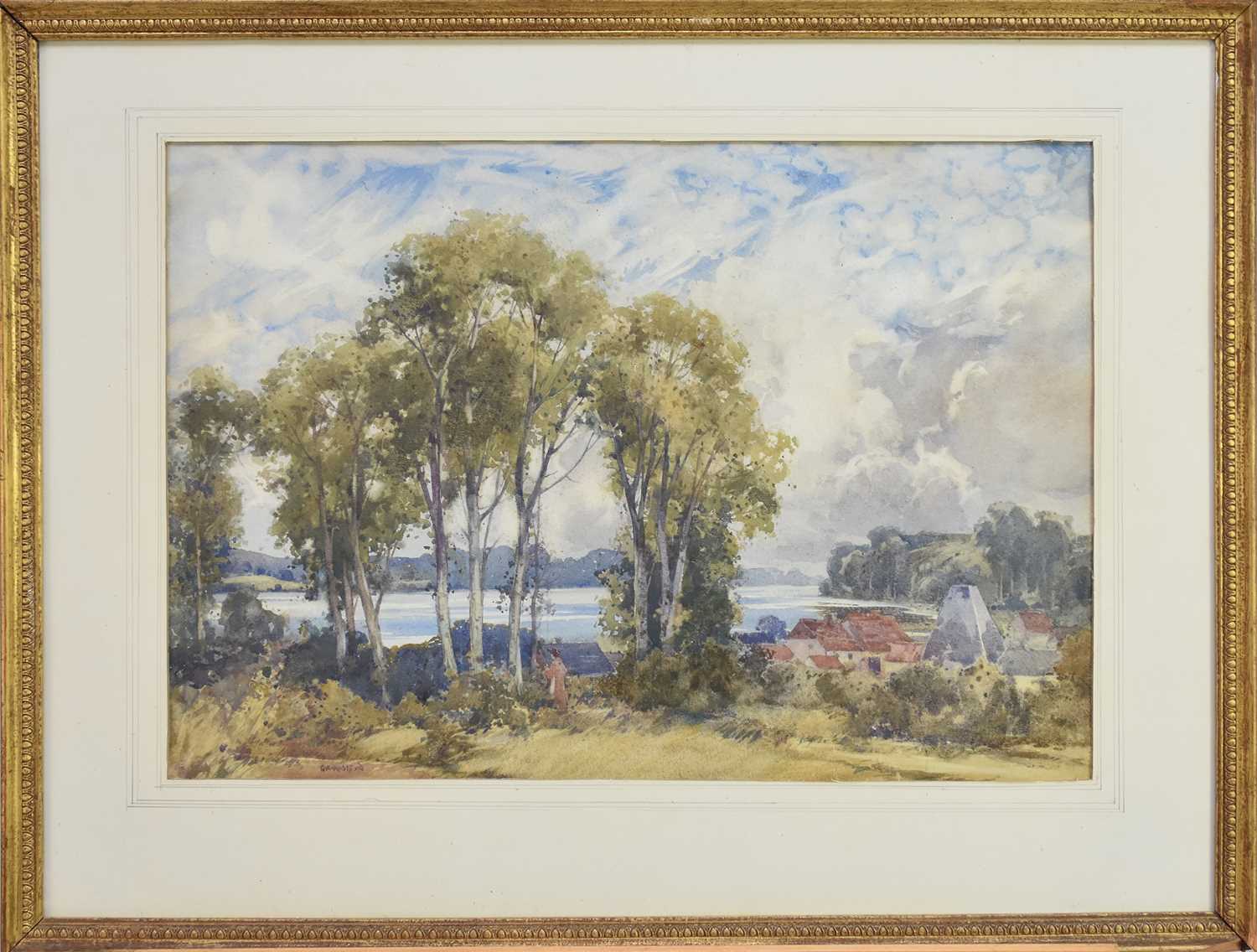 Lot 175 - George Robert Rushton (1869-1947) Lady walking amongst trees with a lakeside village beyond