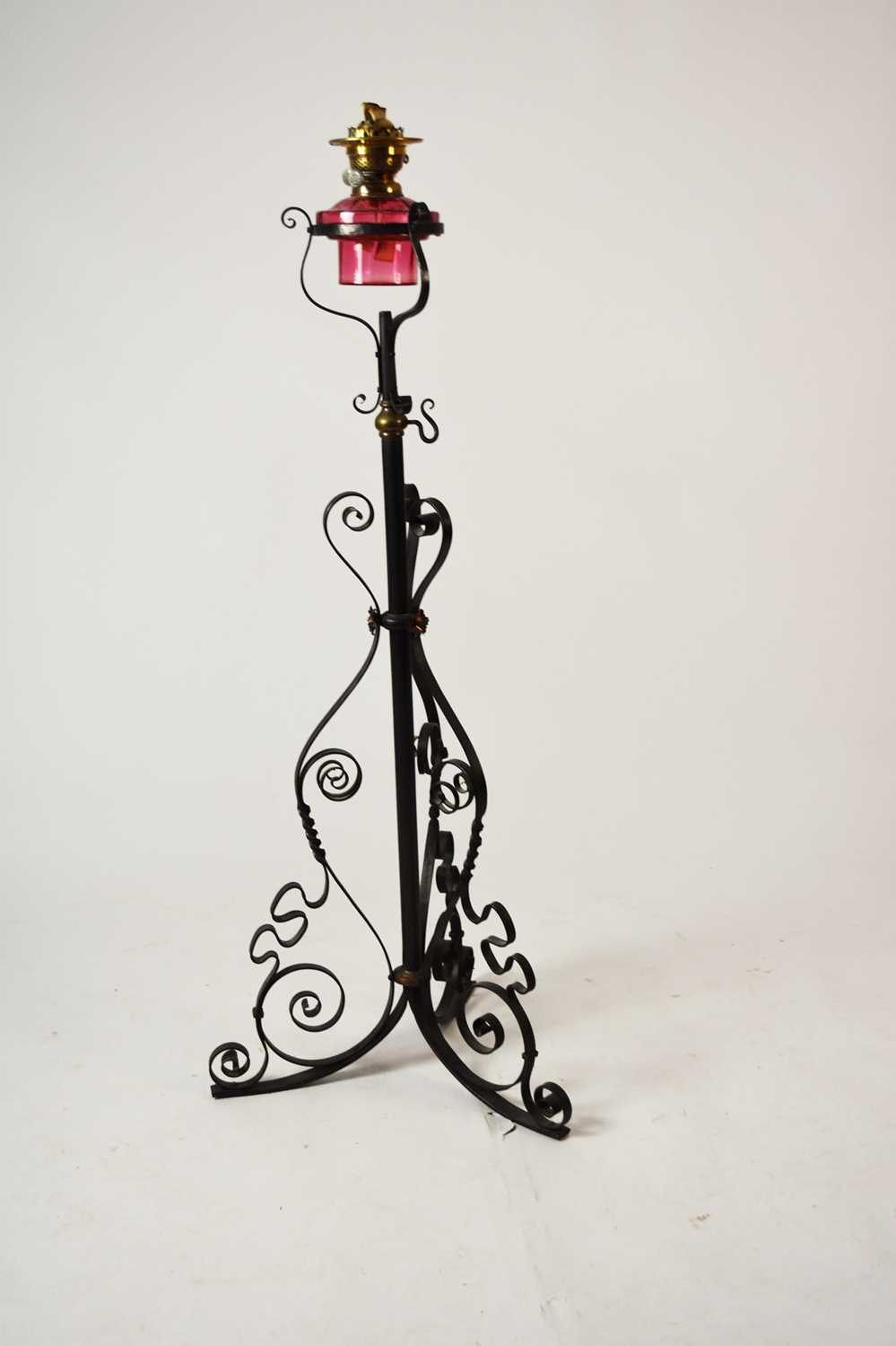 Lot 606 - A wrought iron and cranberry glass oil lamp standard