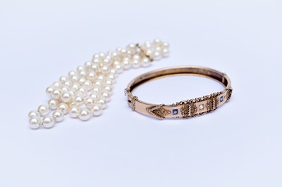 Lot 99 - A diamond and blue stone set hinged bangle and a simulated pearl necklace
