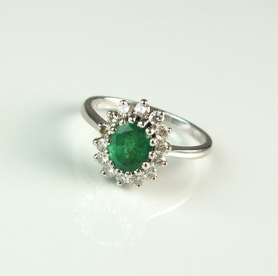 Lot 85 - An 18ct gold emerald and diamond oval cluster ring