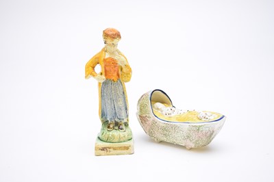 Lot 424 - Prattware child in cradle and Staffordshire pearlware figure