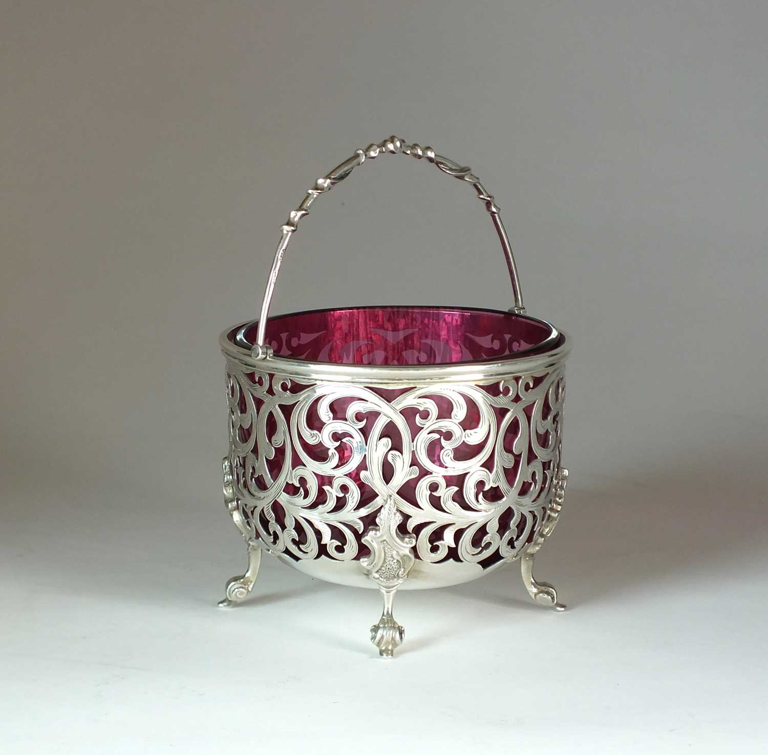 Lot 27 - A Victorian pierced silver sugar basket with cranberry glass liner