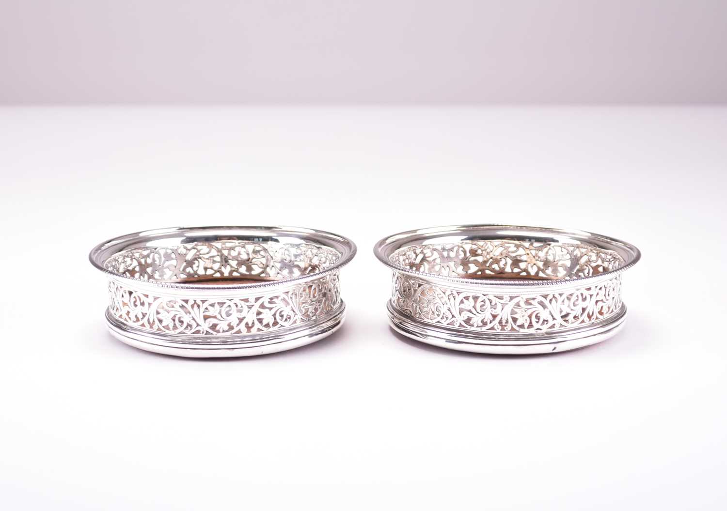 Lot 24 - A pair of George III silver mounted wine coasters