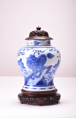 Lot 27 - A Chinese blue and white jar with wood cover and stand, Kangxi (cracked)