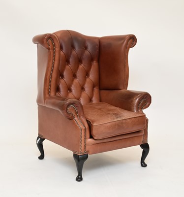 Lot 573 - A reproduction tan leather wing armchair