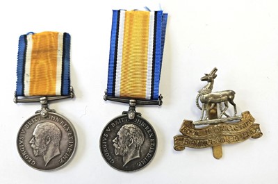 Lot 98 - Two single First World War Medals and a re-strike cap badge.