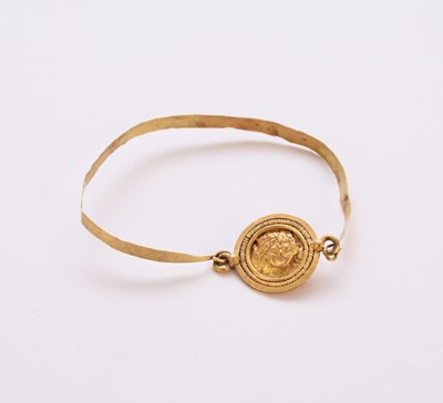 Lot 247 - A yellow metal bangle with Gorgonian medallion