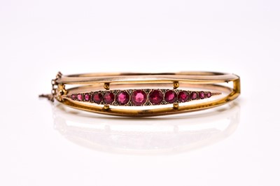 Lot 147 - A 9ct gold graduated red paste set hinged bangle