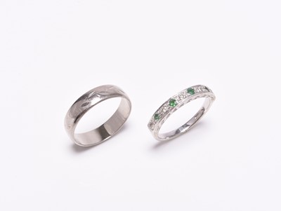 Lot 391 - An 18ct white gold wedding band and an emerald and diamond ring