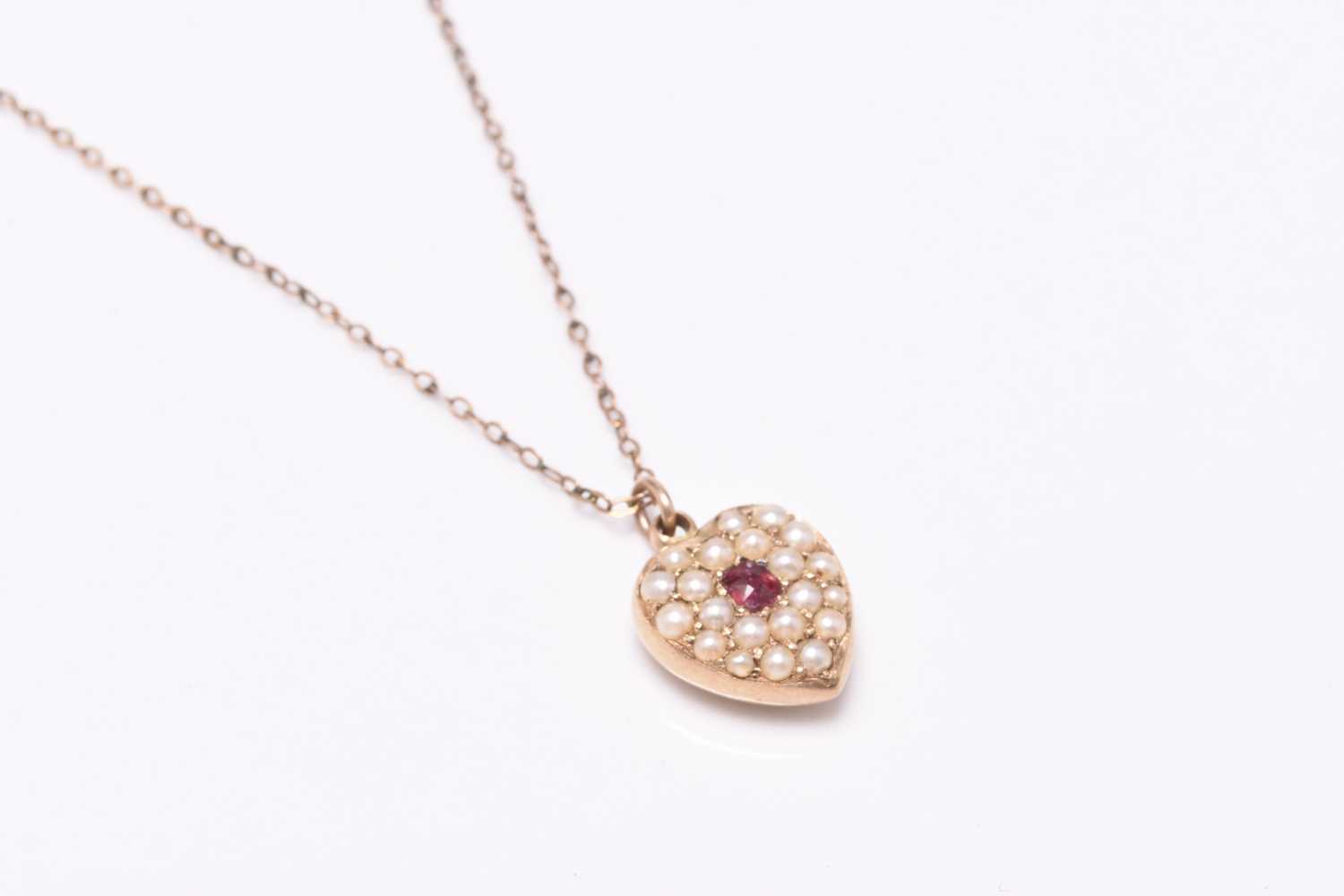 Lot 81 - A late 19th / early 20th century seed pearl and ruby set heart pendant
