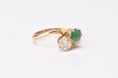 Lot 130 - A two stone emerald and diamond crossover ring