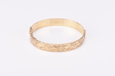 Lot 145 - A 9ct gold bright cut engraved hinged bangle