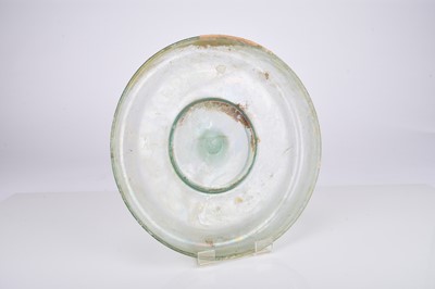 Lot 26 - A Roman pale green glass footed dish, 2nd-3rd century AD