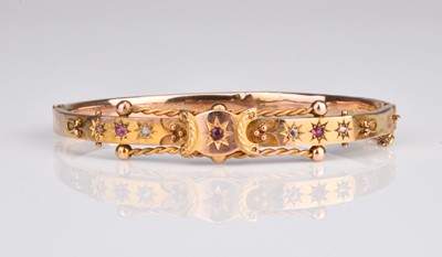 Lot 333 - An Edwardian 9ct gold diamond and red paste hinged bangle