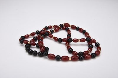 Lot 305 - A graduated ‘cherry red amber' and black bead necklace