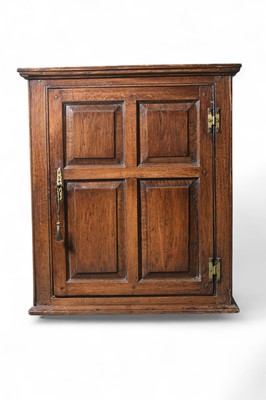 Lot 92 - A George III oak panelled wall hanging cupboard