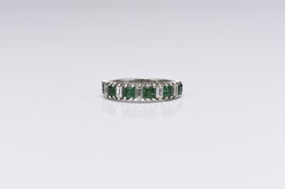 Lot 231 - An emerald and diamond half eternity ring