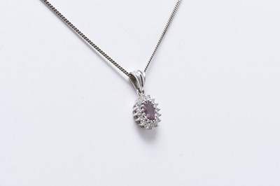 Lot 228 - A 9ct white gold pink sapphire and diamond oval cluster pendant