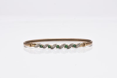 Lot 111 - A 9ct gold emerald and diamond bangle