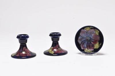 Lot 141 - A pair of Moorcroft candlesticks and a small bowl in the 'Clematis' pattern