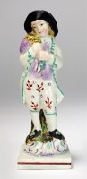 Lot 13 - A pearlware modelled as a boy standing holding...