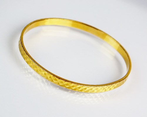 Lot 145 - A yellow metal bangle, indistinctly stamped,...