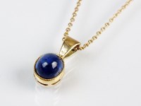 Lot 213 - An oval cabochon sapphire pendant, within...