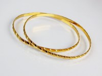 Lot 234 - Two yellow metal bangles, stamped 'CM22c',...